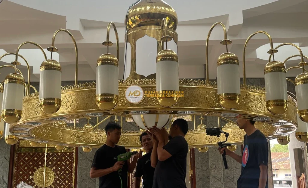 10 Inspirasi Lampu Gantung Ruang Tamu Custom: Material Tembaga Kuningan Langsung Pengrajin 7 Lampu gantung ruang tamu Nabawi super mewah, desain kuningan elegan dengan ukiran kaligrafi dan motif Islami detail, kaca hias berkilau, memancarkan cahaya hangat, menciptakan suasana megah, eksklusif, dan berkelas pada interior rumah bernuansa klasik Arab.